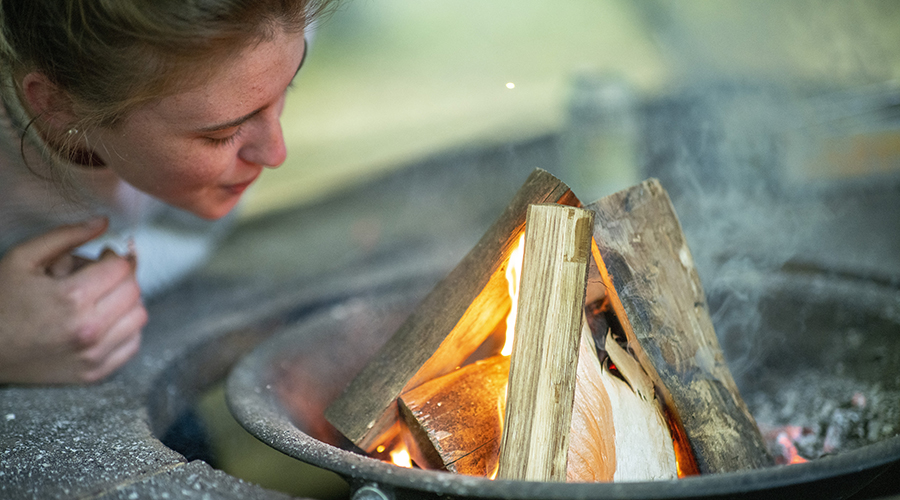 Lady learning how to light a campfire